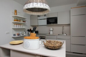Una cocina moderna con armarios blancos, un microondas, una cafetera y un cuenco de mimbre en la encimera.