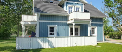 A two-story house with a blue exterior and white trim, a covered porch, and a fenced yard.