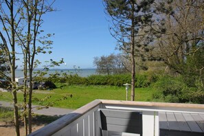 Vista da un balcone su una zona verde con uno specchio d'acqua sullo sfondo.