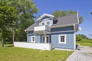 A two-story house with a balcony, a satellite dish, and a paved driveway.