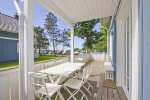 A covered outdoor patio with white furniture and a view of a parking area with RVs. - Vacation home Frigga - comfortable Swedish house close to the beach with sea view - (Wiek)