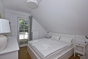 Une chambre à coucher avec un lit, une table de chevet, une lampe et une fenêtre donnant sur un paysage verdoyant.