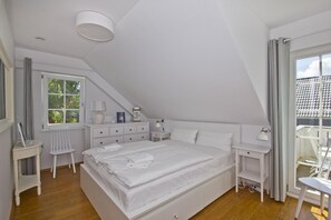 A bedroom with a large bed, a desk, a chair, and a window with curtains. - Vacation home Frigga - comfortable Swedish house close to the beach with sea view - (Wiek)