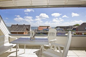 A terrace with a table and chairs, overlooking a residential area with houses and a body of water. - Apartment near the harbor with balcony and sea view - Hafenhäuser Breege FeWo 14 - (Breege)