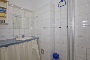 A bathroom with a white sink, a mirror, and a shower area. - Apartment near the harbor with balcony and sea view - Hafenhäuser Breege FeWo 14 - (Breege)