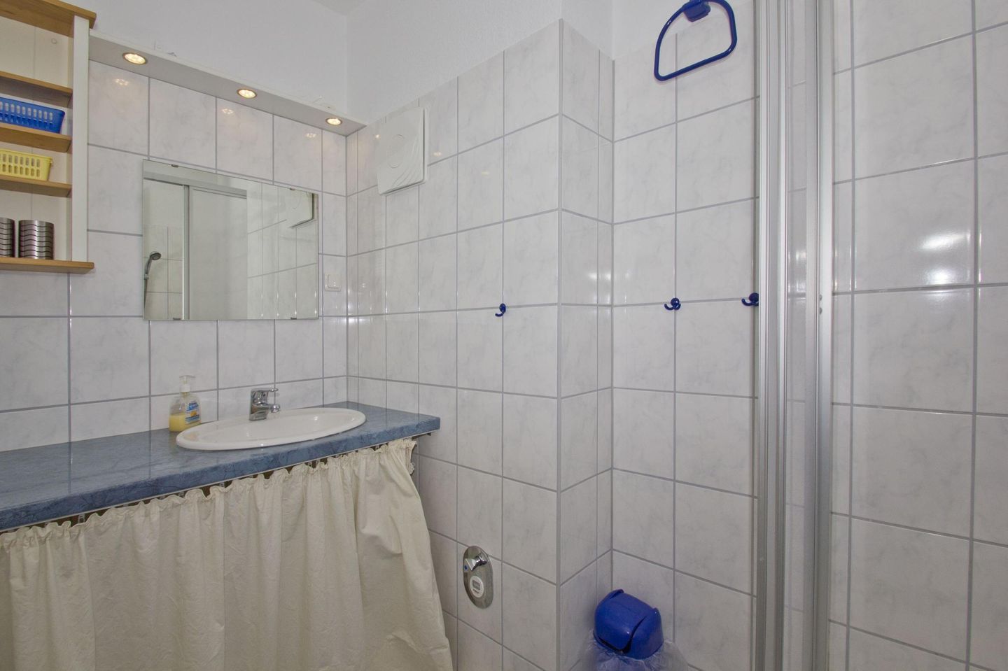 Ein Badezimmer mit Waschbecken, Spiegel und Duschbereich.