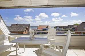 Una terraza con mesa y sillas, con vistas a una zona residencial con casas y un cuerpo de agua.