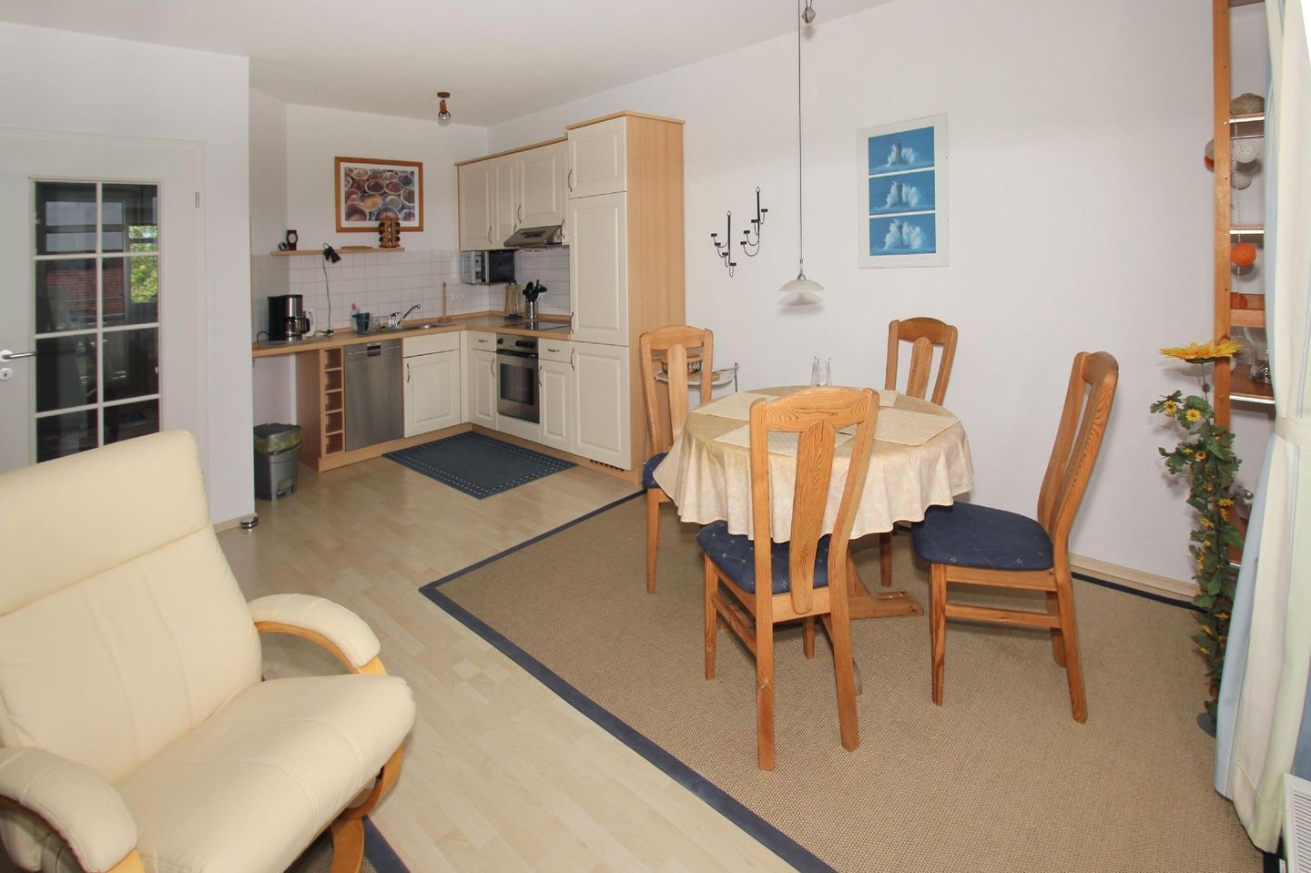 A compact living space with a dining area, kitchen, and a seating area with a sofa and chairs.