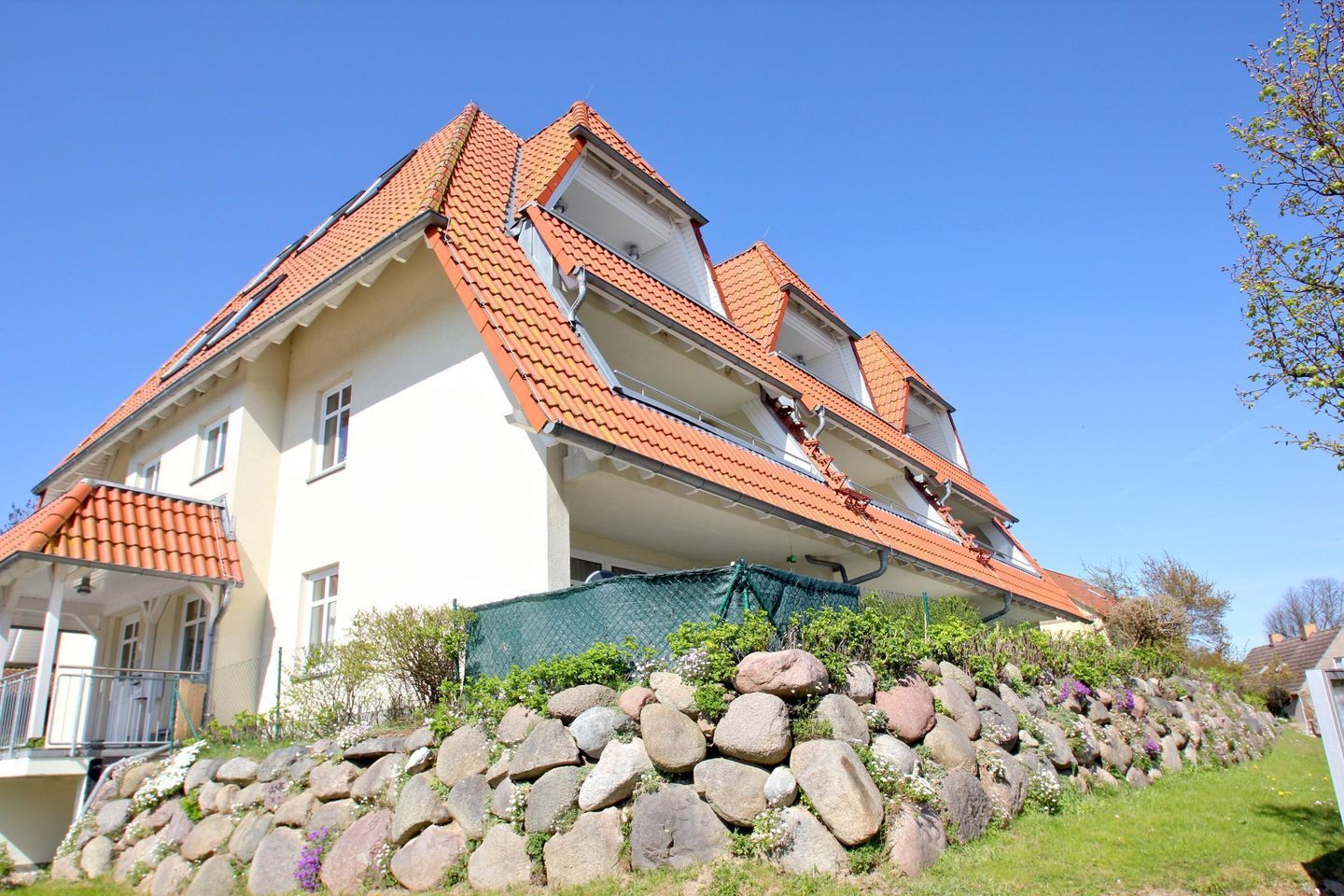 Une maison à deux étages, avec un toit recouvert de tuiles rouges et un mur de pierre à l’avant.