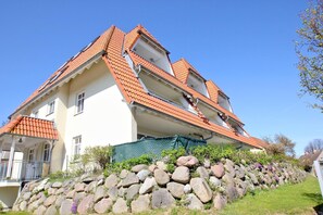 Ein zweistöckiges Haus mit rotem Ziegeldach und einer Steinwand vor der Fassade.