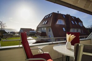 A balcony with a table and chairs, overlooking a residential area with houses and a body of water. - 2-room vacation apartment near the harbor with balcony - Hafenhäuser Breege FeWo 05 - (Breege)