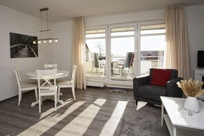 En moderne stue med spiseplads, store vinduer og udsigt til det fri.