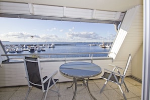 Ein Balkon mit Tisch und Stühlen mit Blick auf eine Marina und Boote.