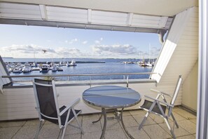 A balcony with a table and chairs, overlooking a marina with boats. - Apartment near the harbor with balcony and sea view - Hafenhäuser Wiek 07 - (Wiek)