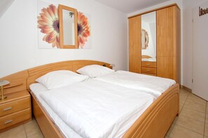 Un dormitorio con una cama de madera, una mesita de noche, un aparador y un espejo grande.