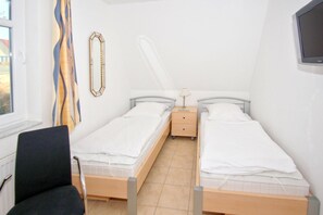 A small, clean room with two single beds, a chair, a nightstand, and a TV on the wall. - Apartment near the harbor with balcony and sea view - Hafenhäuser Wiek 15 - (Wiek)