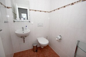 A small bathroom with a white sink, toilet, and a trash can. - Apartment near the harbor with balcony and sea view - Hafenhäuser Wiek 11 - (Wiek)