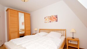 A bedroom with a bed, wooden wardrobe, bedside tables, and a ceiling light.