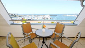 A balcony with two chairs and a small table, overlooking a marina with boats.