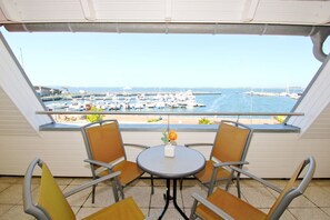 A balcony with two chairs and a small table, overlooking a marina with boats. - Apartment near the harbor with balcony and sea view - Hafenhäuser Wiek FeWo 01 - (Wiek)