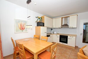 Una cocina compacta con una mesa y sillas de madera, un microondas, una estufa y un lavaplatos.