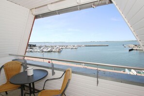 A balcony with wicker chairs and a table, overlooking a marina with boats and a pier. - Apartment near the harbor with balcony and sea view - Hafenhäuser Wiek 17 - (Wiek)