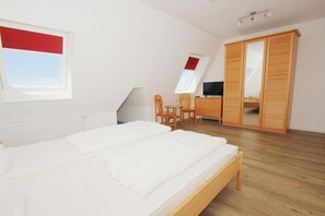 A bedroom with a bed, a desk, a chair, a wardrobe, and a window. - Apartment near the harbor with balcony and sea view - Hafenhäuser Wiek 17 - (Wiek)