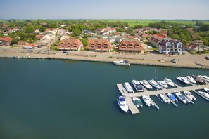 Un port de plaisance où sont amarrés des bateaux, entouré de bâtiments résidentiels et de verdure.