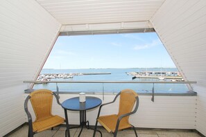 A balcony with two wicker chairs and a small table, overlooking a marina with boats and a pier. - Apartment near the harbor with balcony and sea view - Hafenhäuser Wiek 17 - (Wiek)