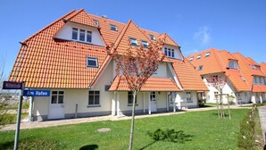 A row of houses with orange tiled roofs and white walls, a clear blue sky, and a sign indicating 'Mittelstraße Am Hafen'. - Apartment near the harbor with balcony and sea view - Hafenhäuser Wiek FeWo 03 - (Wiek)
