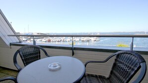 A balcony with a table and two chairs, overlooking a marina with boats docked. - Apartment near the harbor with balcony and sea view - Hafenhäuser Wiek FeWo 03 - (Wiek)