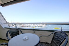 A balcony with a table and two chairs, overlooking a marina with boats docked. - Apartment near the harbor with balcony and sea view - Hafenhäuser Wiek FeWo 03 - (Wiek)