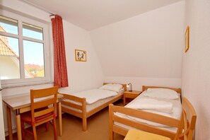 Ein Schlafsaalzimmer mit zwei Einzelbetten, einem Schreibtisch und einem Stuhl.