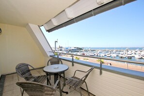 A balcony with wicker chairs and a small table, overlooking a marina with numerous boats. - Apartment near the harbor with balcony and sea view - Hafenhäuser Wiek FeWo 03 - (Wiek)