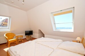 A bedroom with a bed, a television, a chair, and a window. - Apartment near the harbor with balcony and sea view - Hafenhäuser Wiek FeWo 04 - (Wiek)