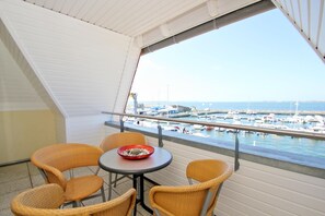 A balcony with wicker chairs and a table, overlooking a marina with boats. - Apartment near the harbor with balcony and sea view - Hafenhäuser Wiek FeWo 04 - (Wiek)