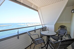 A balcony with a table and chairs, overlooking a marina with boats and a pier. - Apartment near the harbor with a balcony and a view of the sea - Hafenhäuser Wiek 06 - (Wiek)