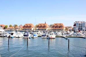 Ein Yachthafen mit vertäuten Booten, Gebäuden mit roten Dächern und wolkenlosem Himmel.