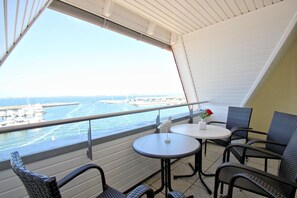 A balcony with a view of the sea, featuring two round tables and wicker chairs. - Apartment near the harbor with balcony and sea view - Hafenhäuser Wiek 05 - (Wiek)