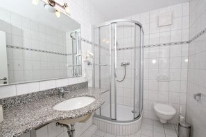 A modern bathroom with a granite countertop sink, a glass-enclosed shower, and a white toilet. - Apartment near the harbor with balcony and sea view - Hafenhäuser Wiek 05 - (Wiek)