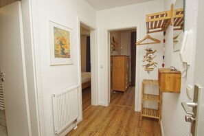 A hallway with a radiator, a bed, a wooden cabinet, and a wooden shelf with items. - Apartment Neptun - cozy 3-room apartment with terrace and garden - (Breege)