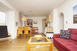 Una sala de estar moderna con un sofá rojo, una mesa de centro de madera y un comedor con una mesa y sillas de madera.