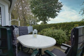 An outdoor patio with a round table, chairs, and a lantern.