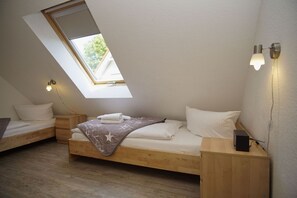 Une chambre avec un puits de lumière, un lit avec une couverture, des tables de chevet et des lampes fixées au mur.