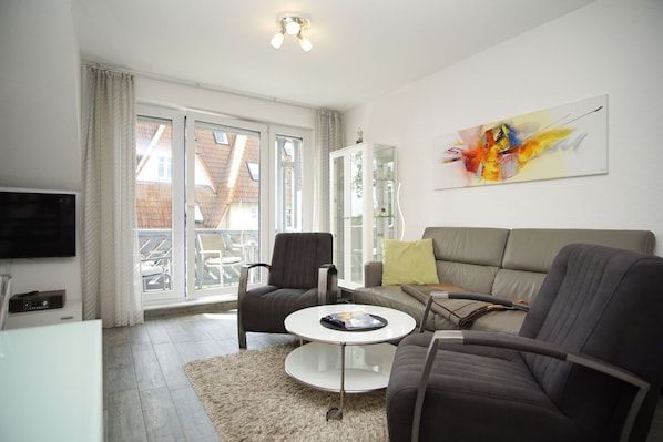 A modern living room with a grey sofa, a round coffee table, and a television.
