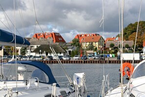 A marina with boats docked, a thatched-roof building, and a row of colorful houses in the background.