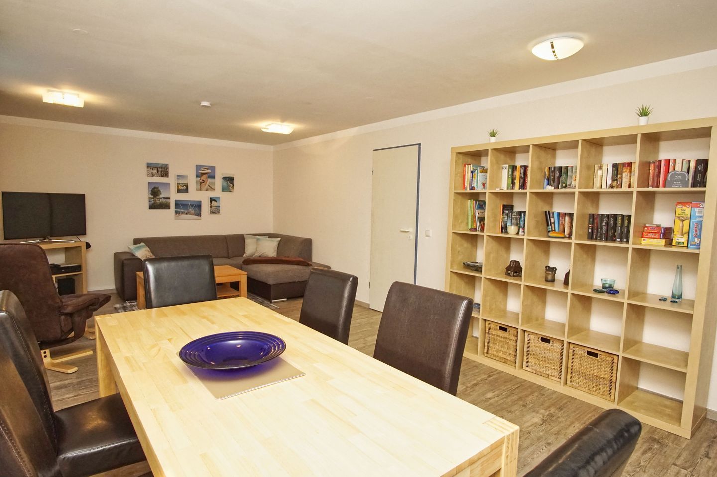 A living room with a wooden table, leather chairs, a bookshelf, and a television.