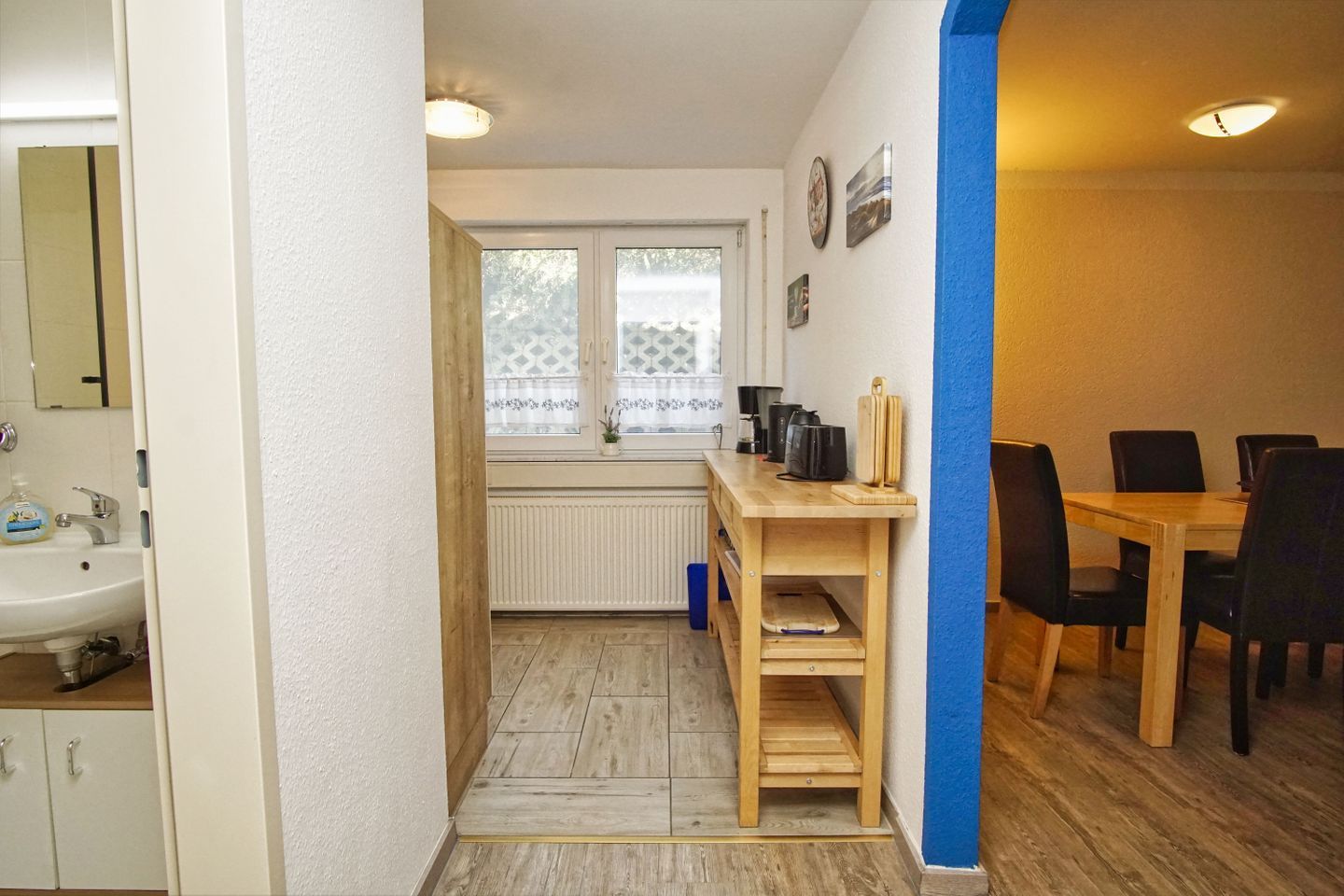 A compact kitchen with a wooden table, a sink, and a window with frosted glass.