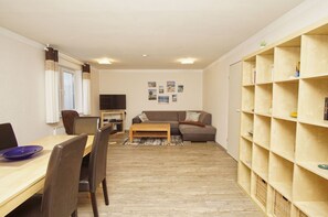 A compact living space with a dining area, a sofa, and a bookshelf.
