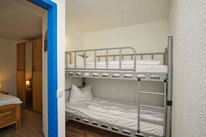 Ein Schlafraum mit Etagenbetten, einer Holztür und einem kleinen Nachttisch mit Lampe.